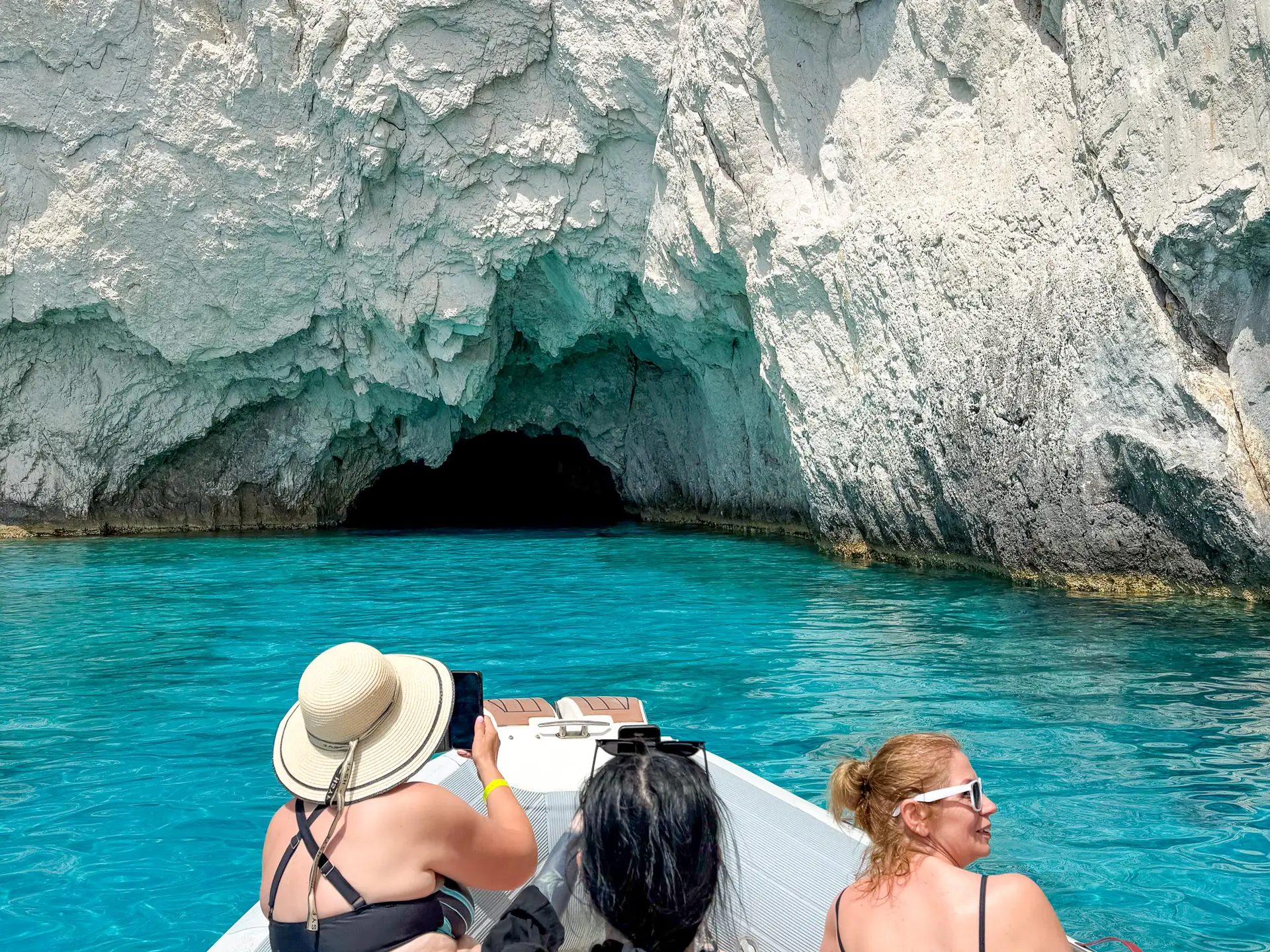 Mała łódź wpływająca do Błękitnych Grot przylądka Keri na południowo-zachodnim wybrzeżu Zakynthos, otoczona turkusową wodą i wapiennymi skałami.