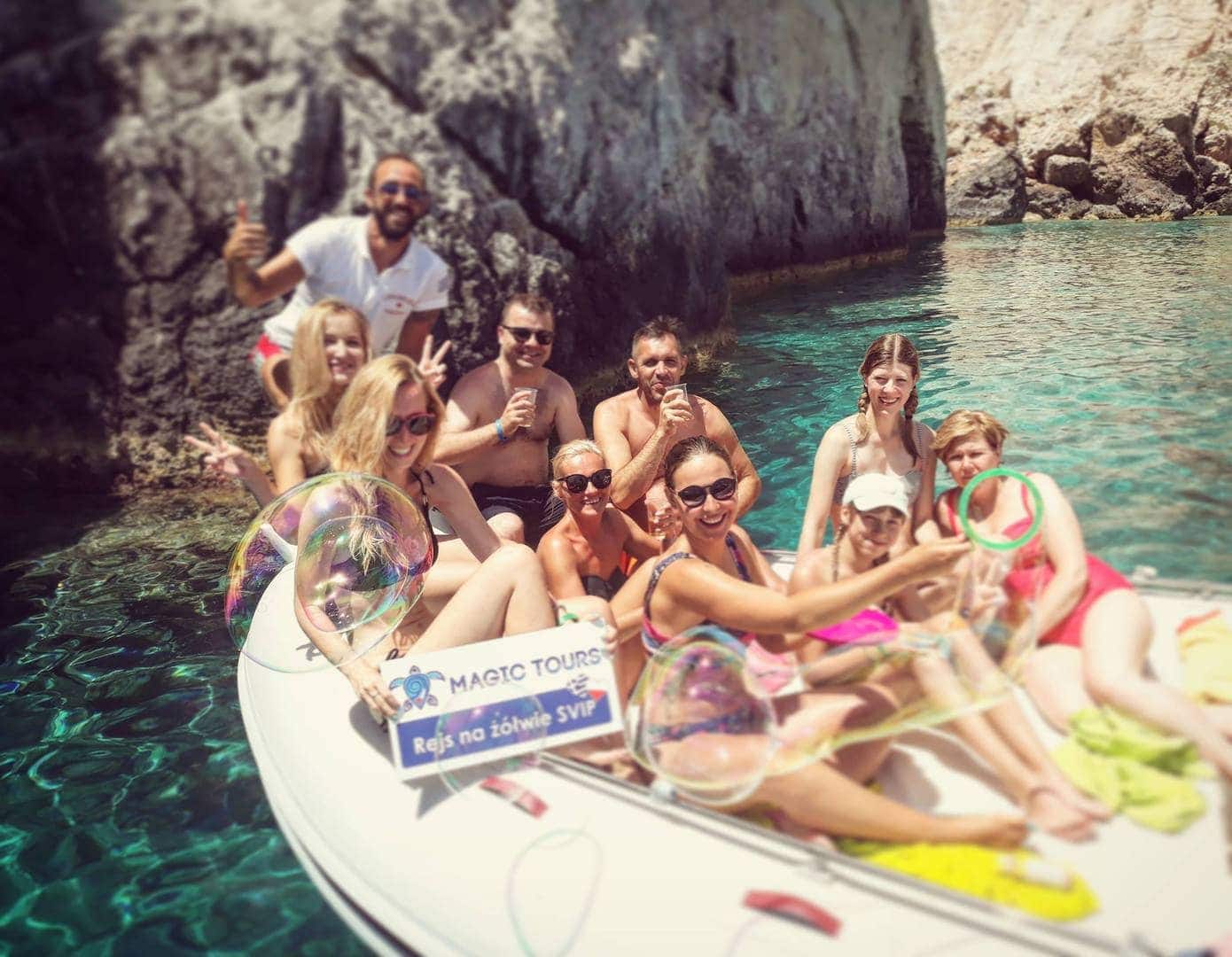 Grupa szczęśliwych i uśmiechniętych turystów na łodzi motorowej Magic Tours na morzu Zakynthos, podczas rejsu w poszukiwaniu żółwi Caretta caretta na wycieczce fakultatywnej na Zakynthos z przewodnikiem