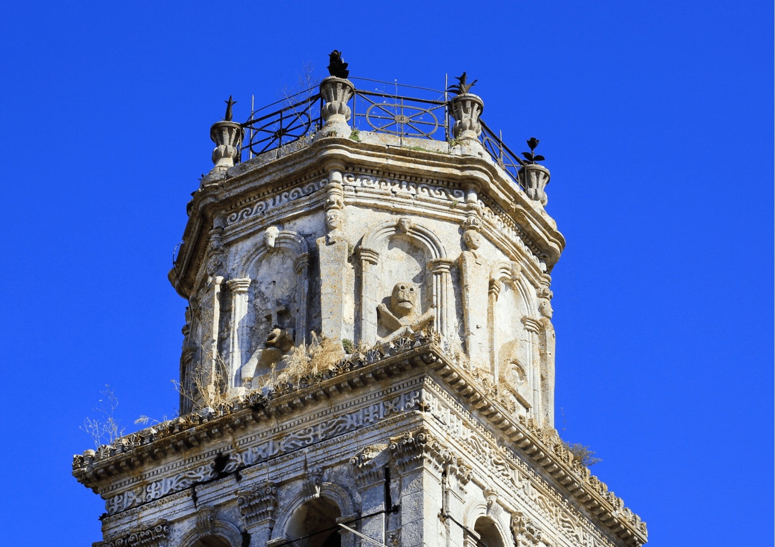 Kamienna wieża kościoła w Kiliomenos na Zakynthos. Kamienna wieża z rzeźbami na Zakynthos na tle bezchmurnego nieba, podczas wycieczki z przewodnikiem po polsku na Zakynthos