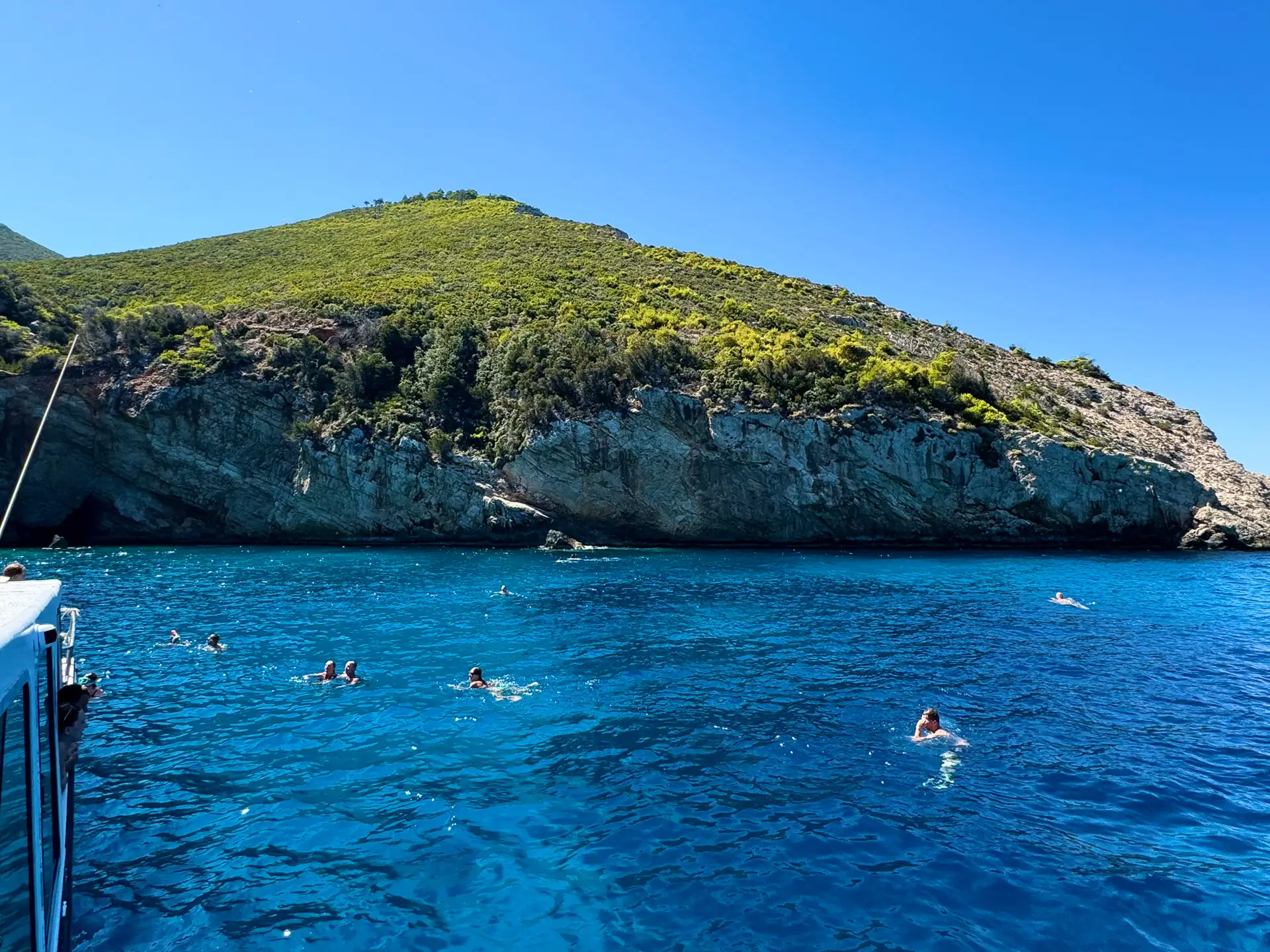 Turyści pływający w lazurowej wodzie zatoki Selinas u wybrzeży Zakynthos podczas rejsu Magic Tours.