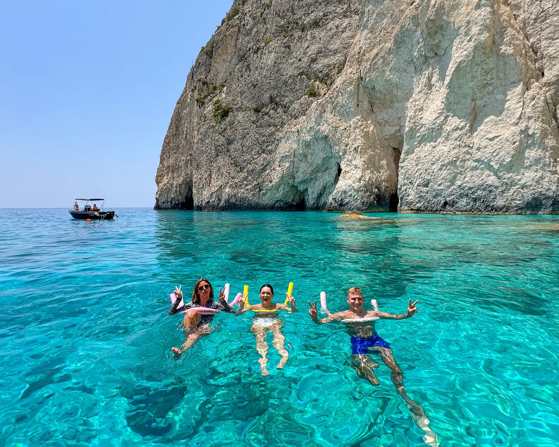 Turyści kąpiący się w turkusowej wodzie przy białych skałach Mizithres na południowym Zakynthos.